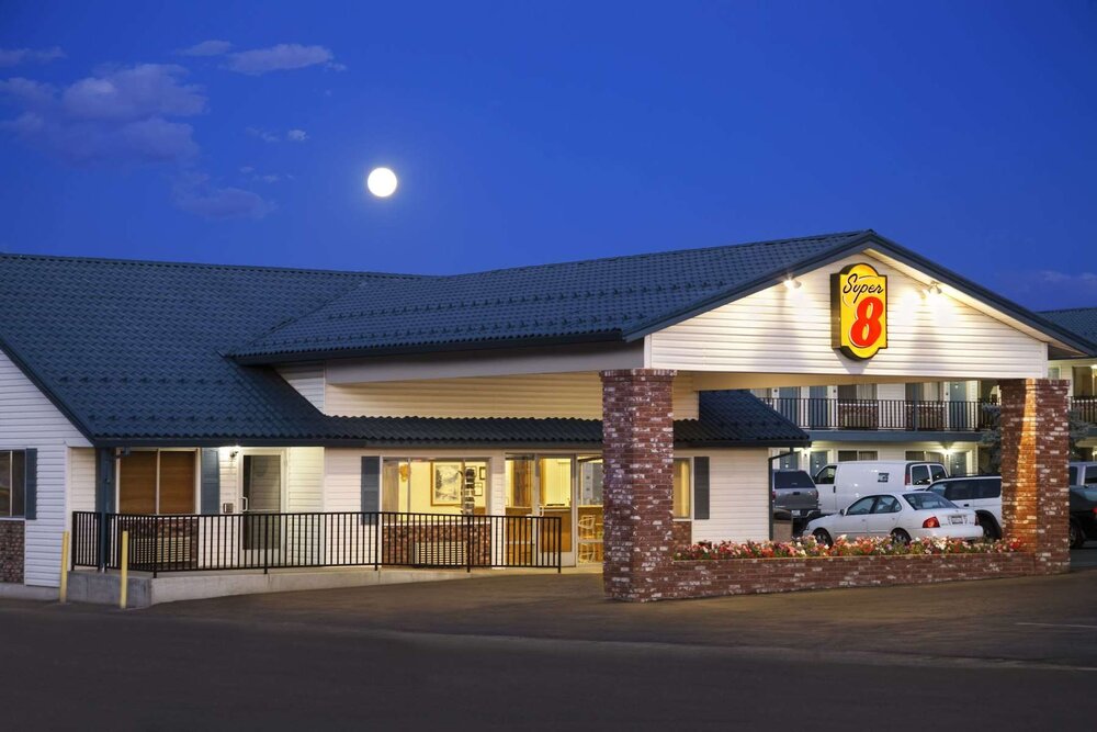 Super 8 motel exterior at dusk with illuminated sign and a full moon overhead