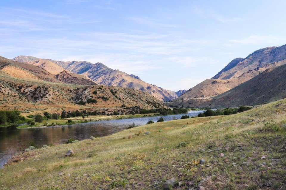 A river winding through a grassy valley flanked by mountains